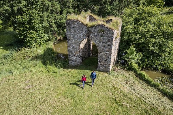 Zwei Wanderer besuchen die Burgruine Steinebach an der Wied. Luftaufnahme 